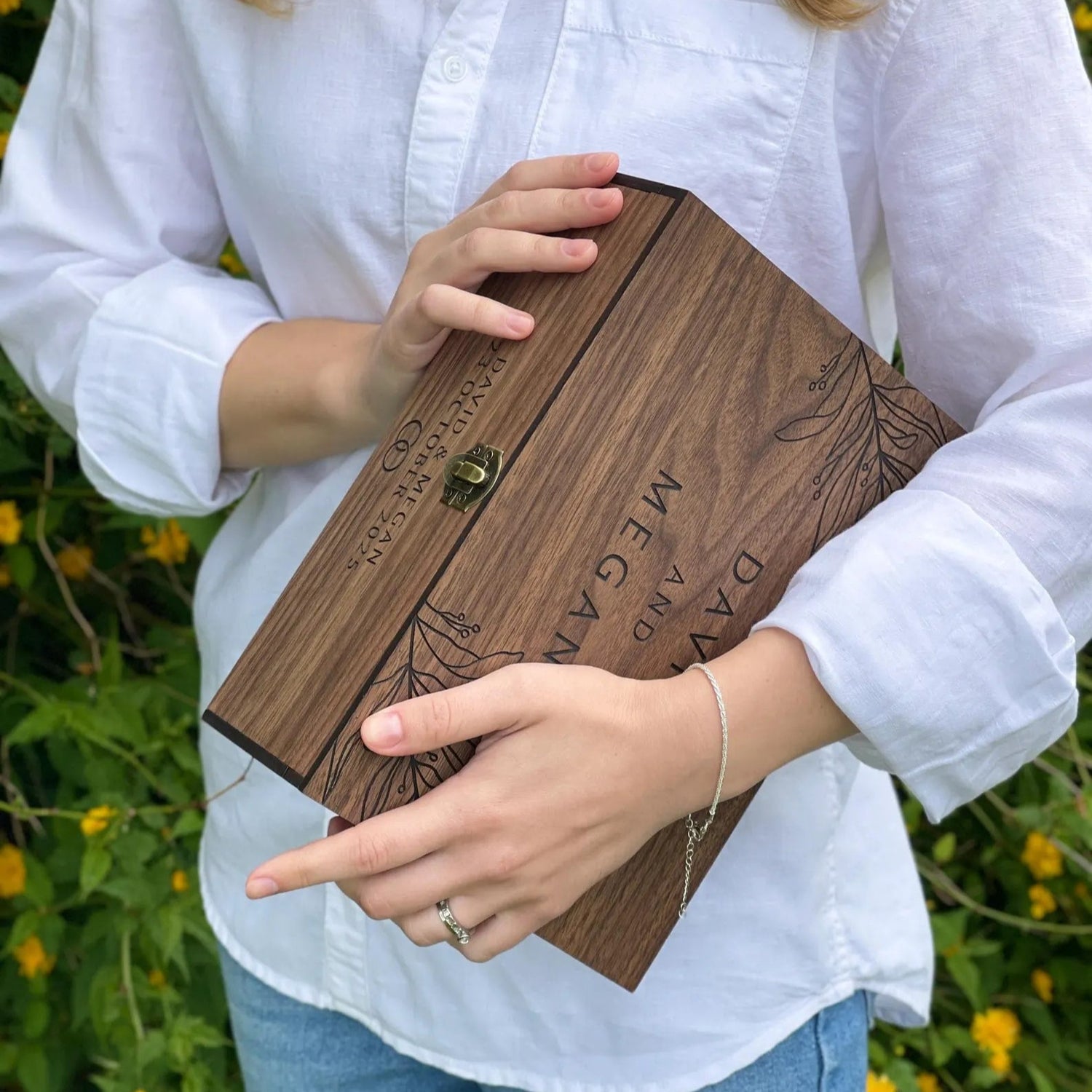 Person holding a wooden box with engraved text against a natural background