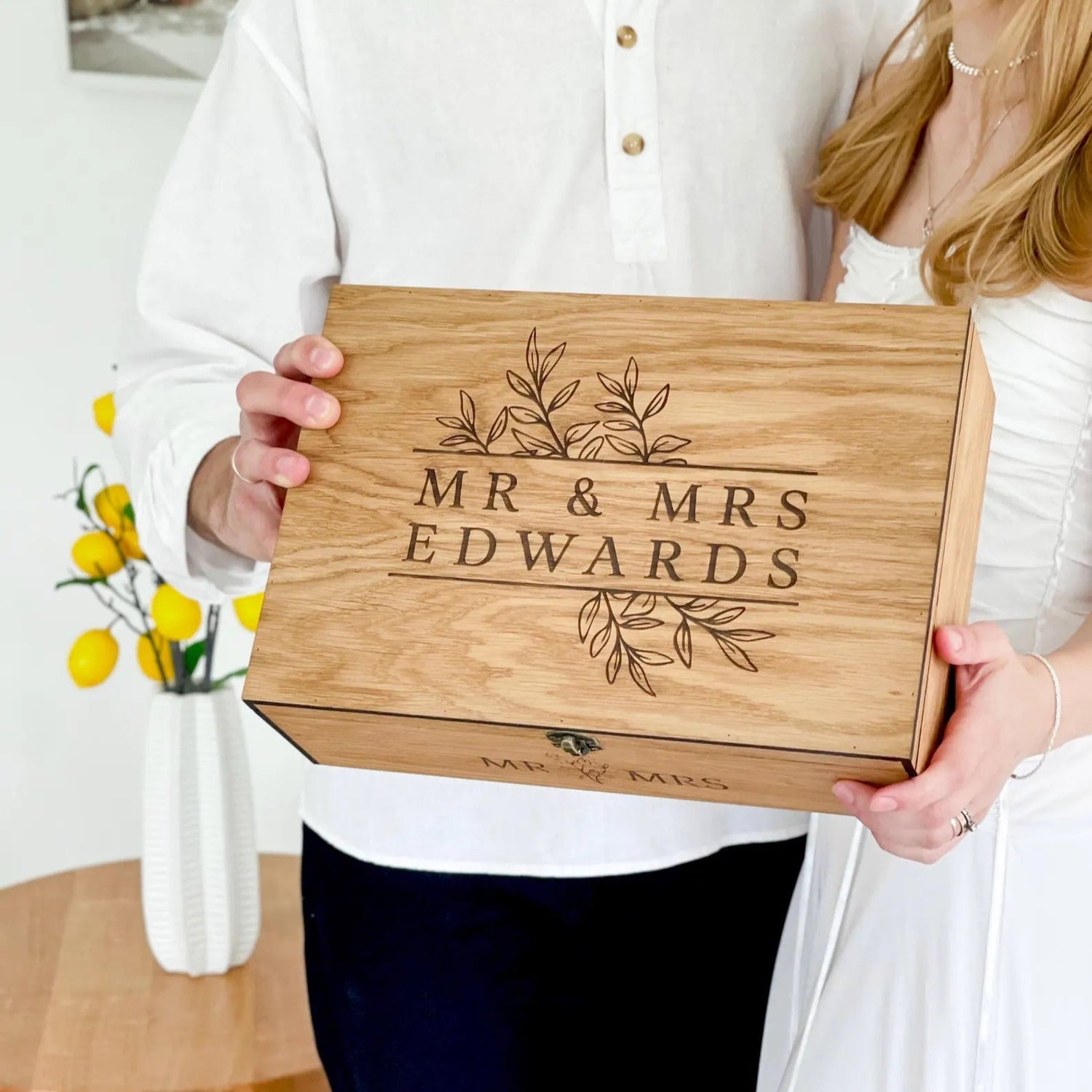 Couple holding a wooden cutting board with 'Mr & Mrs Edwards' engraving.