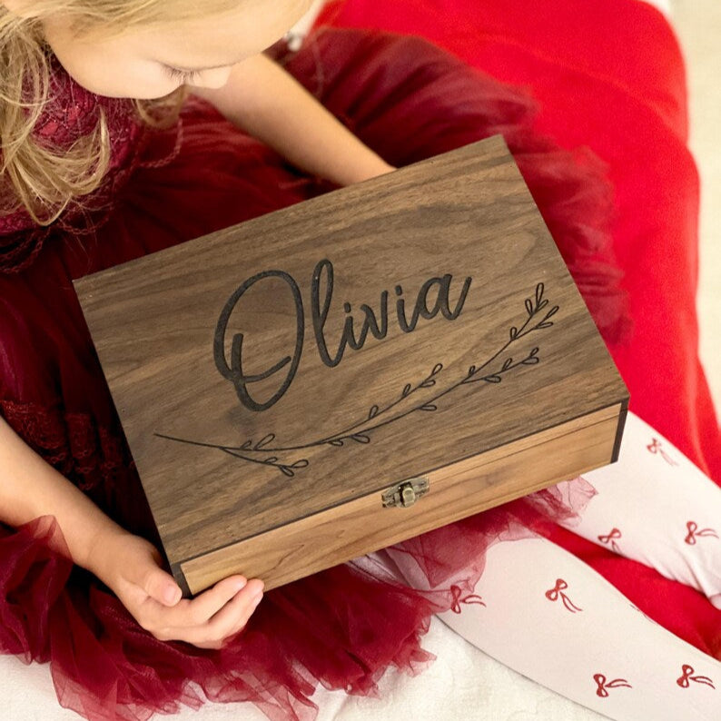 Child holding a wooden box with 'Olivia' engraved on it
