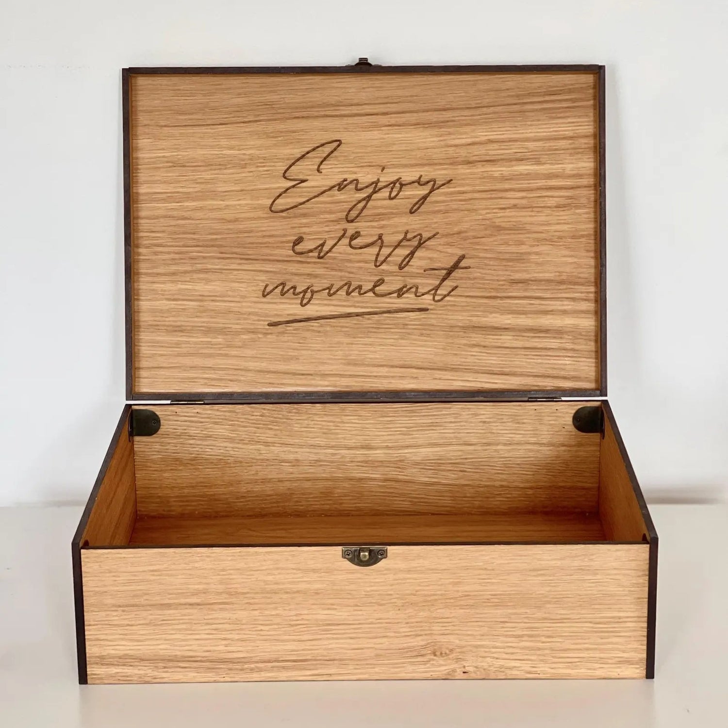 Wooden box with 'Enjoy every moment' engraving on a white background