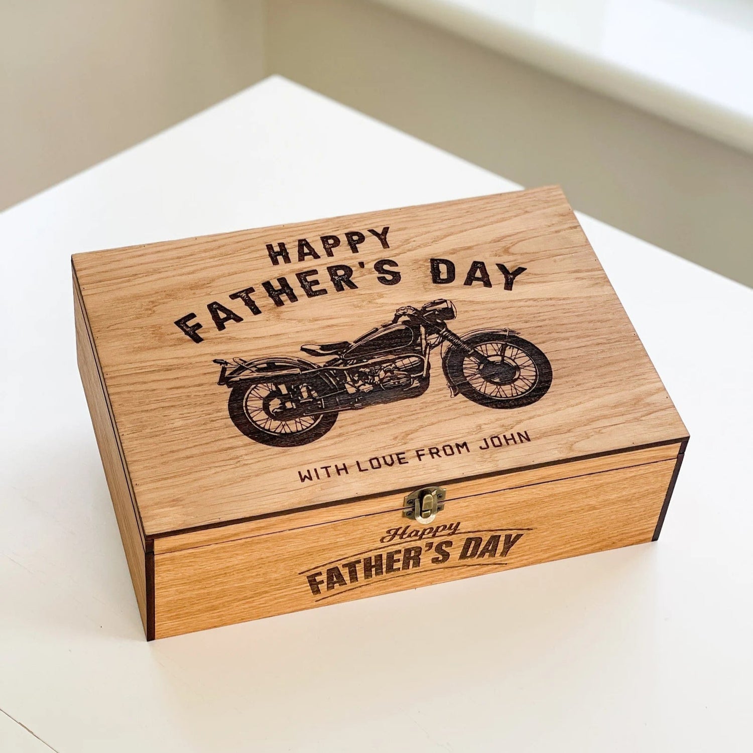 Wooden box with 'Happy Father's Day' and motorcycle engraving on a white surface.
