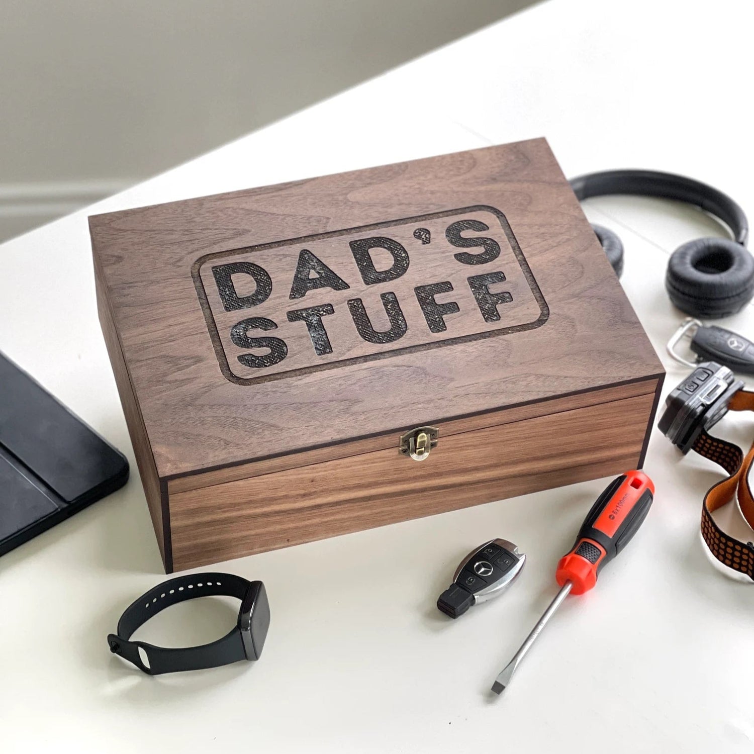 Wooden box labeled 'Dad's Stuff' with tools on a white surface