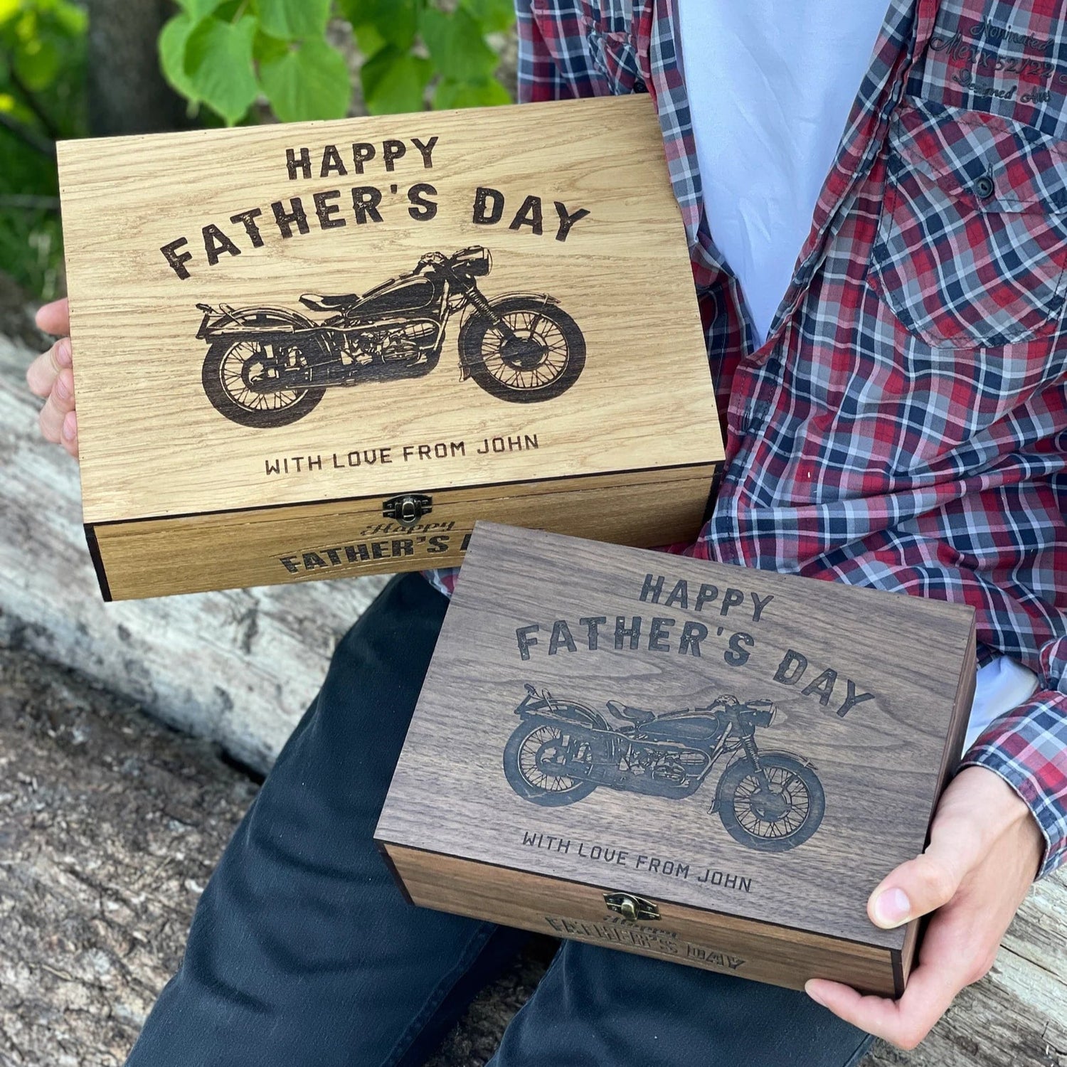 Two wooden Father's Day boxes with motorcycle engraving held by a person outdoors.