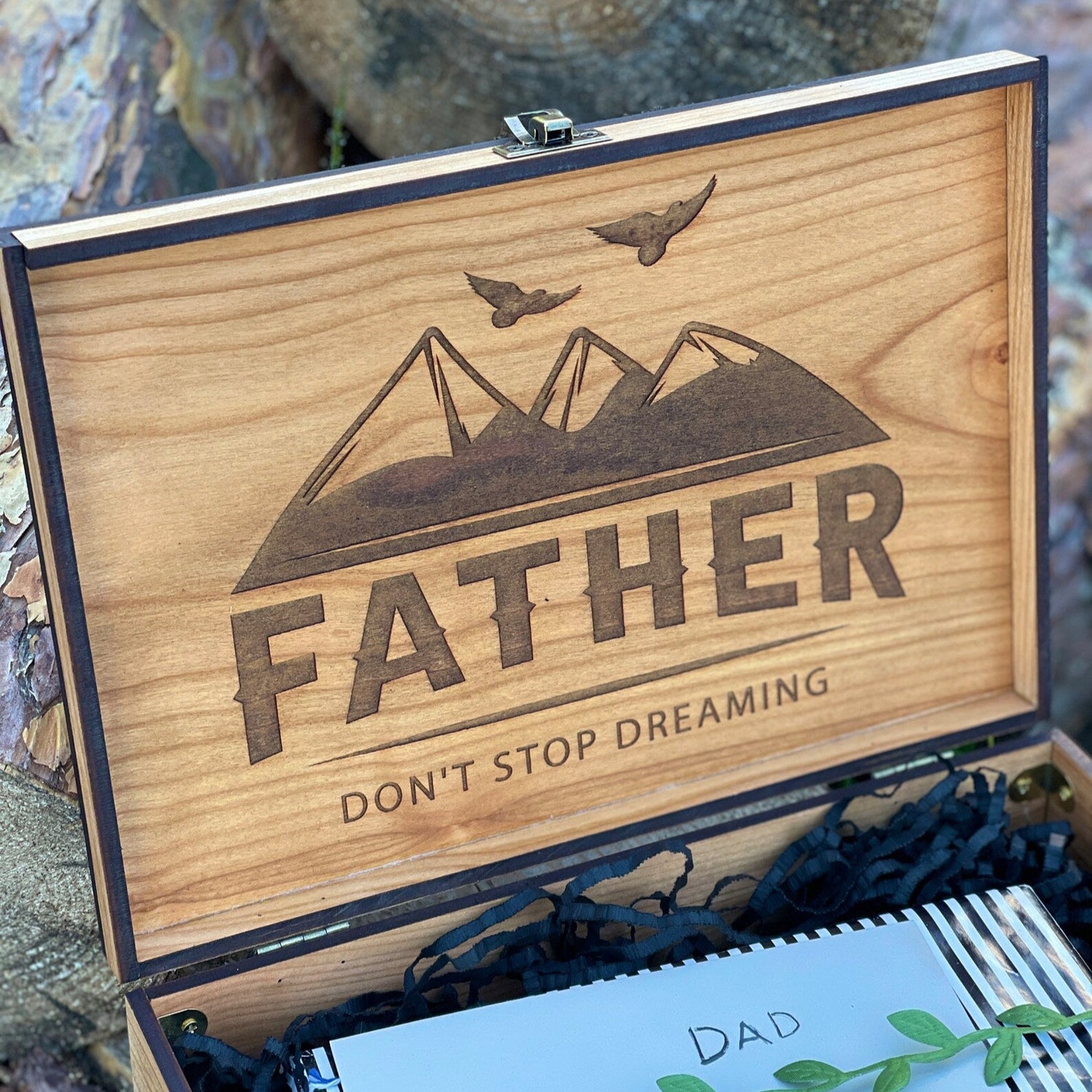 Wooden box with 'Father Don't Stop Dreaming' engraving on a natural background