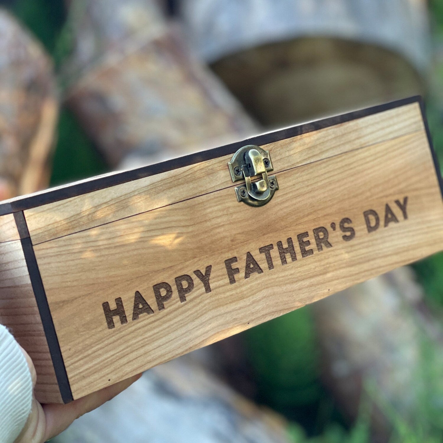Wooden box with 'Happy Father's Day' engraving held against a natural background.