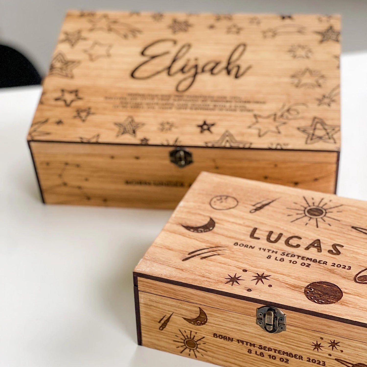 Two wooden boxes with engraved names and dates on a white surface