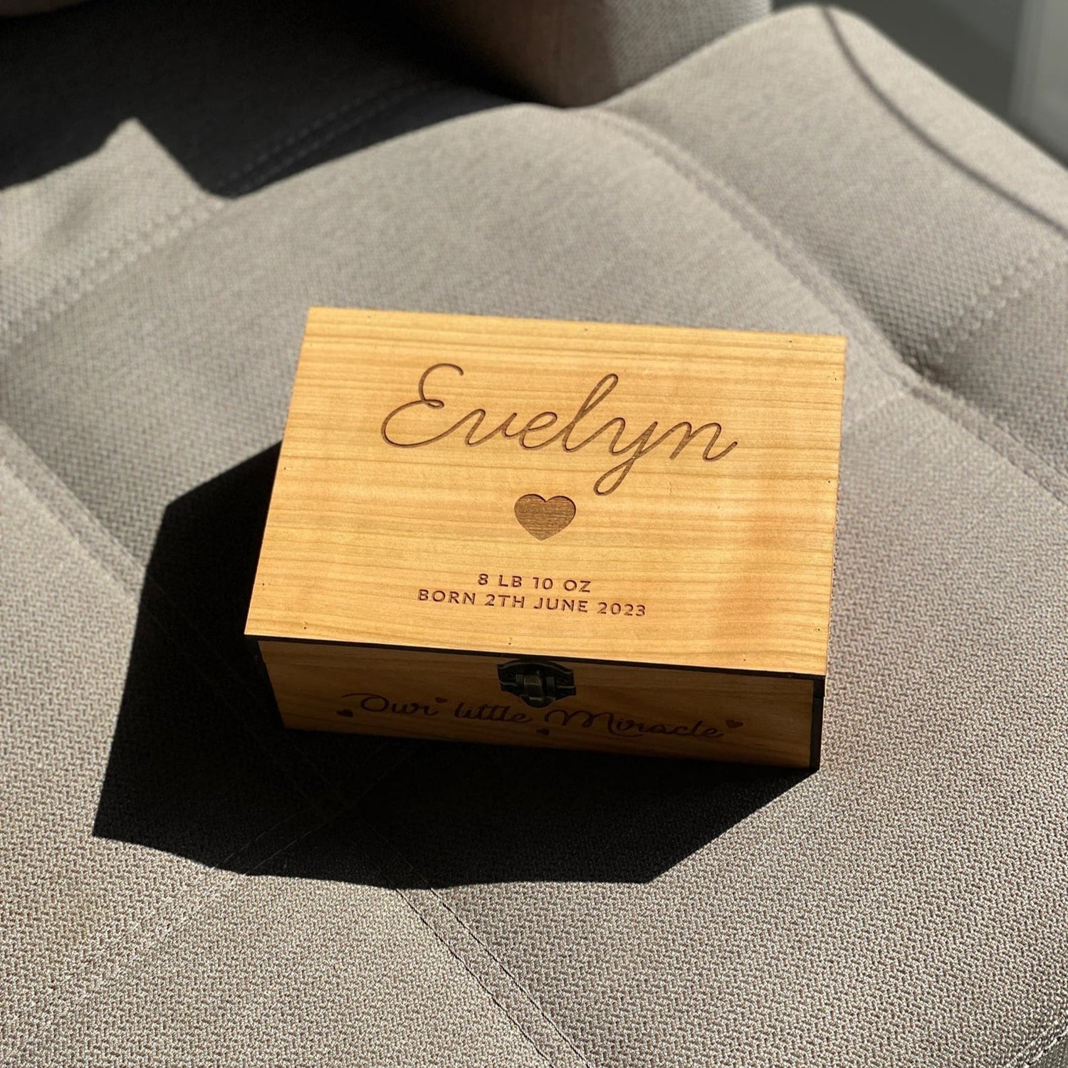 Wooden box engraved with 'Evelyn' and birth details on a textured surface