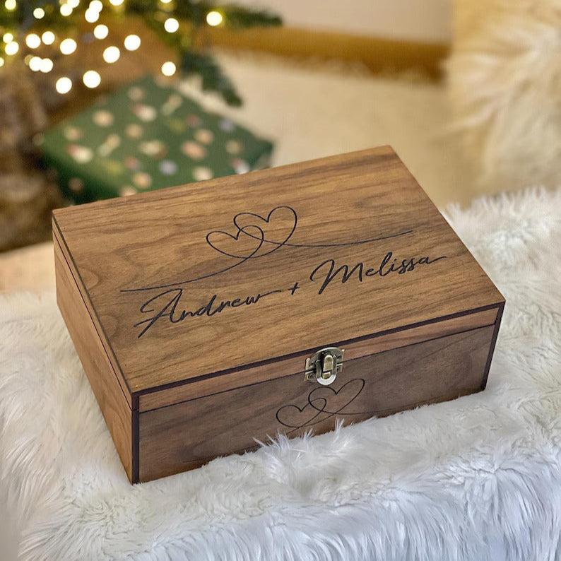 Wooden box with engraved names on a fluffy surface with a Christmas tree in the background