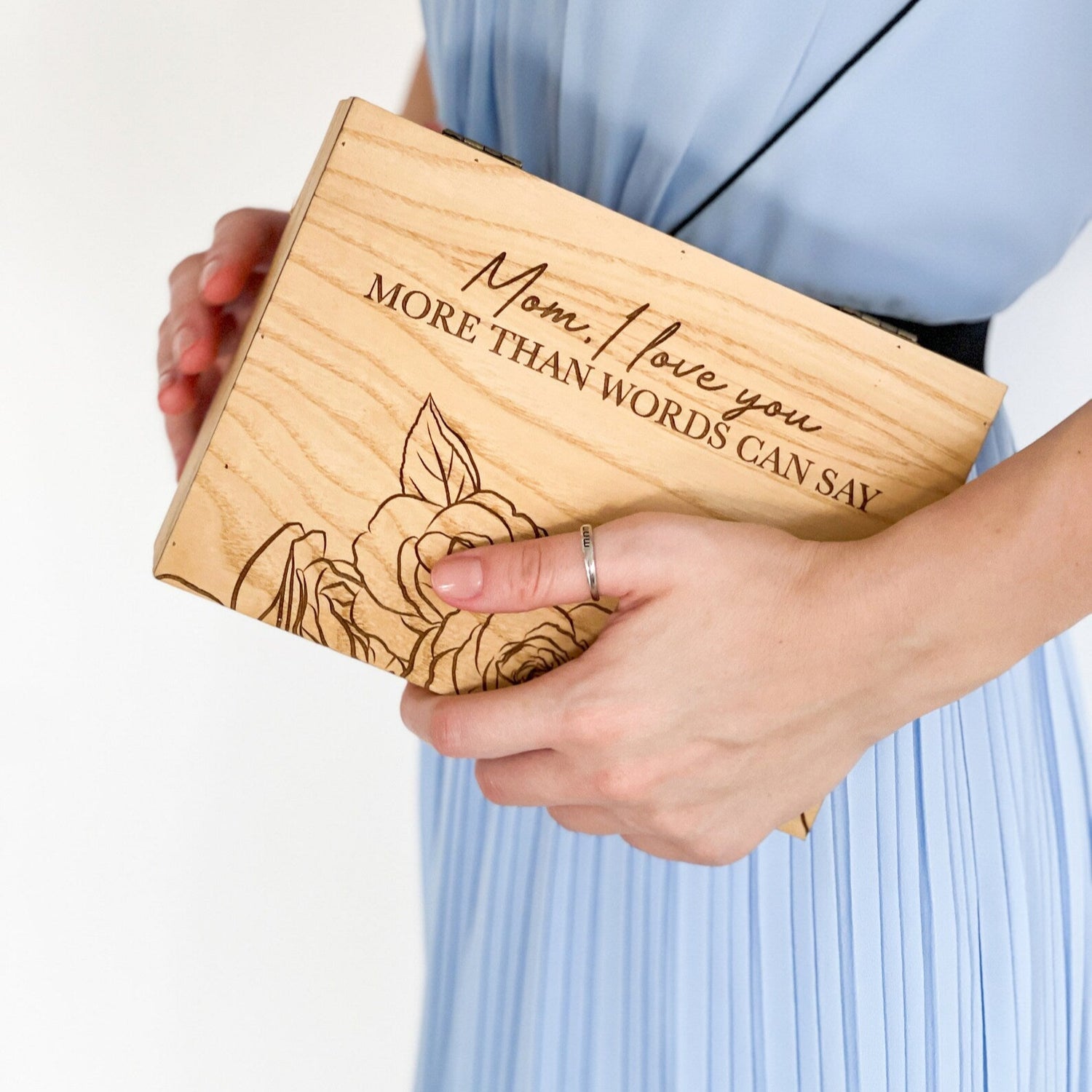 Person holding a wooden box with engraved message and floral design.