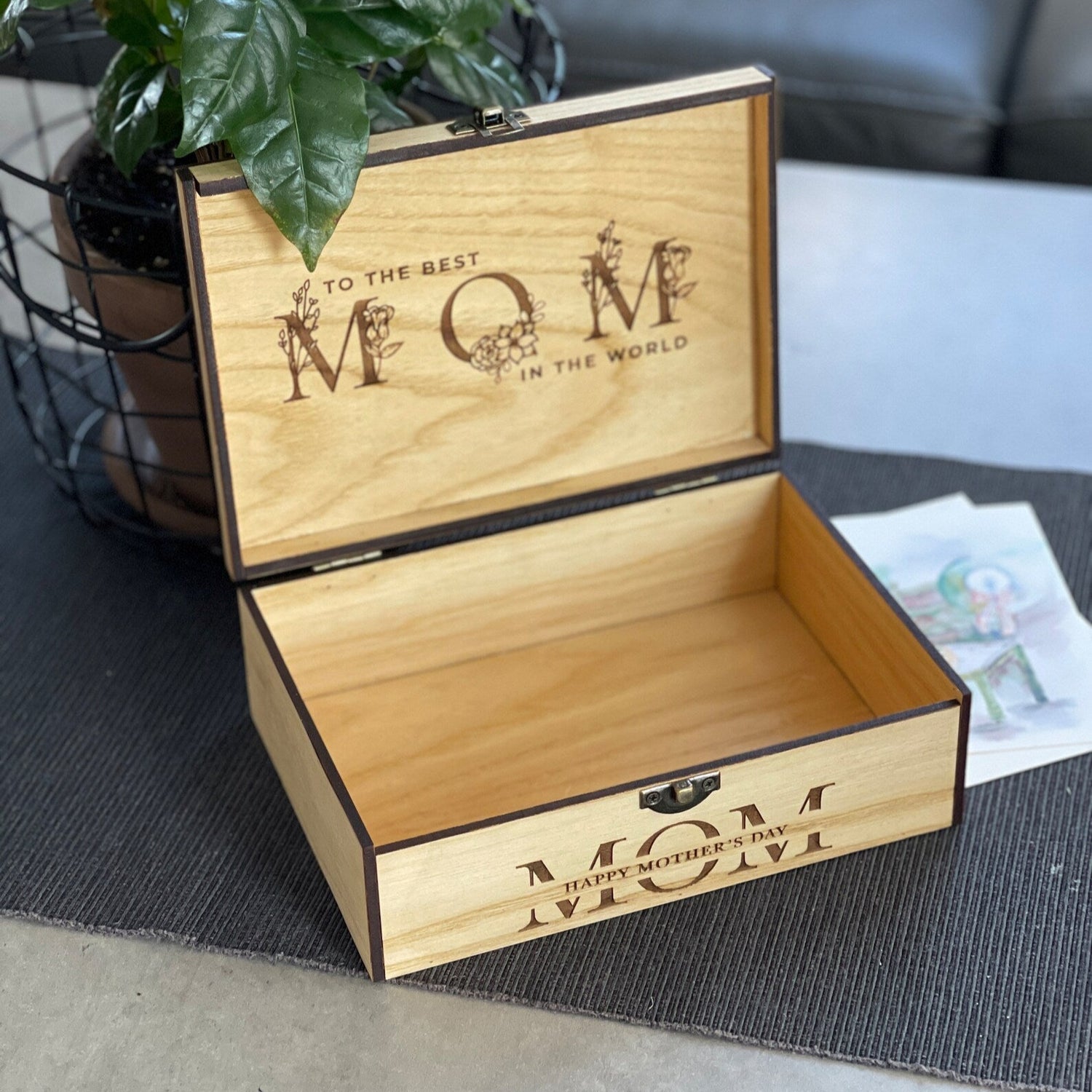 Wooden box engraved with 'To the best MOM in the world' on a table.