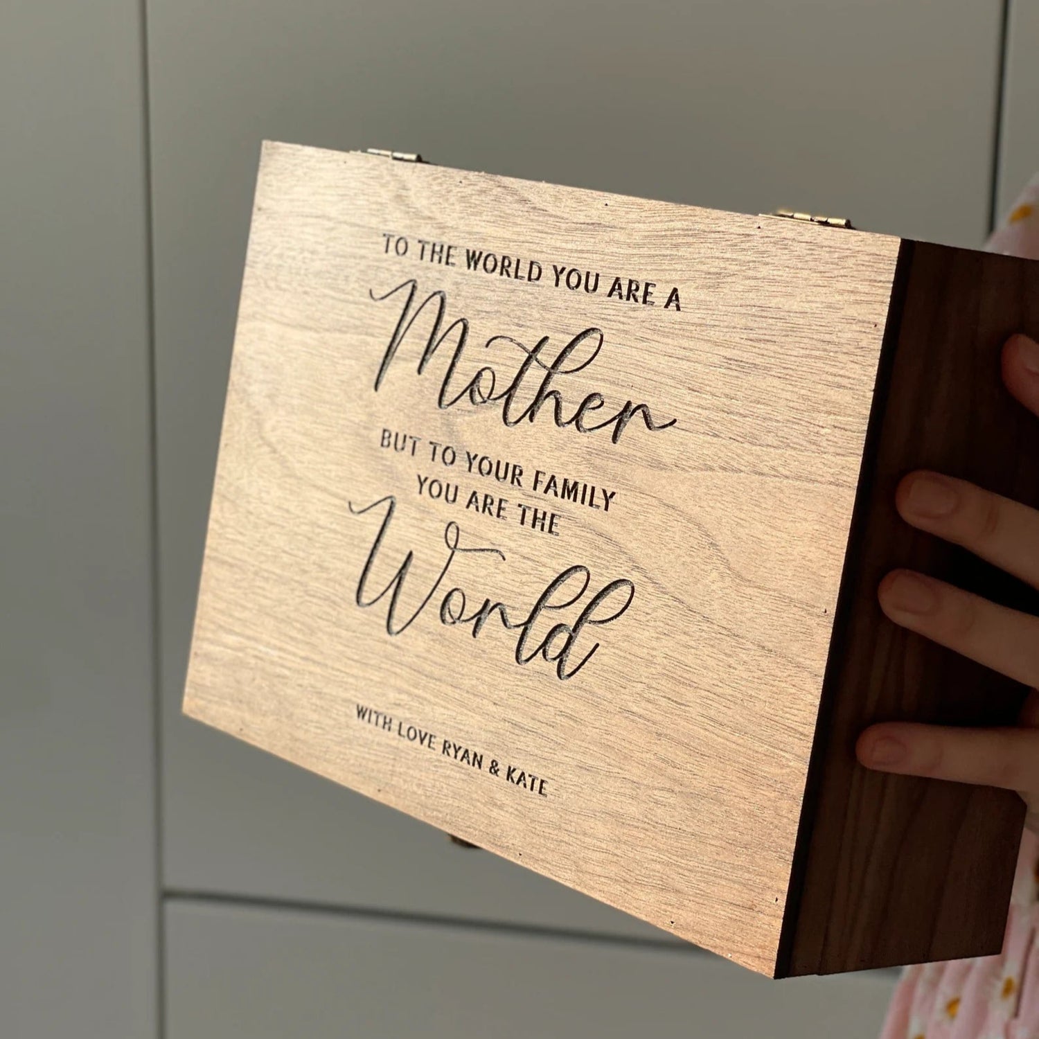 Wooden box with engraved message on a neutral background