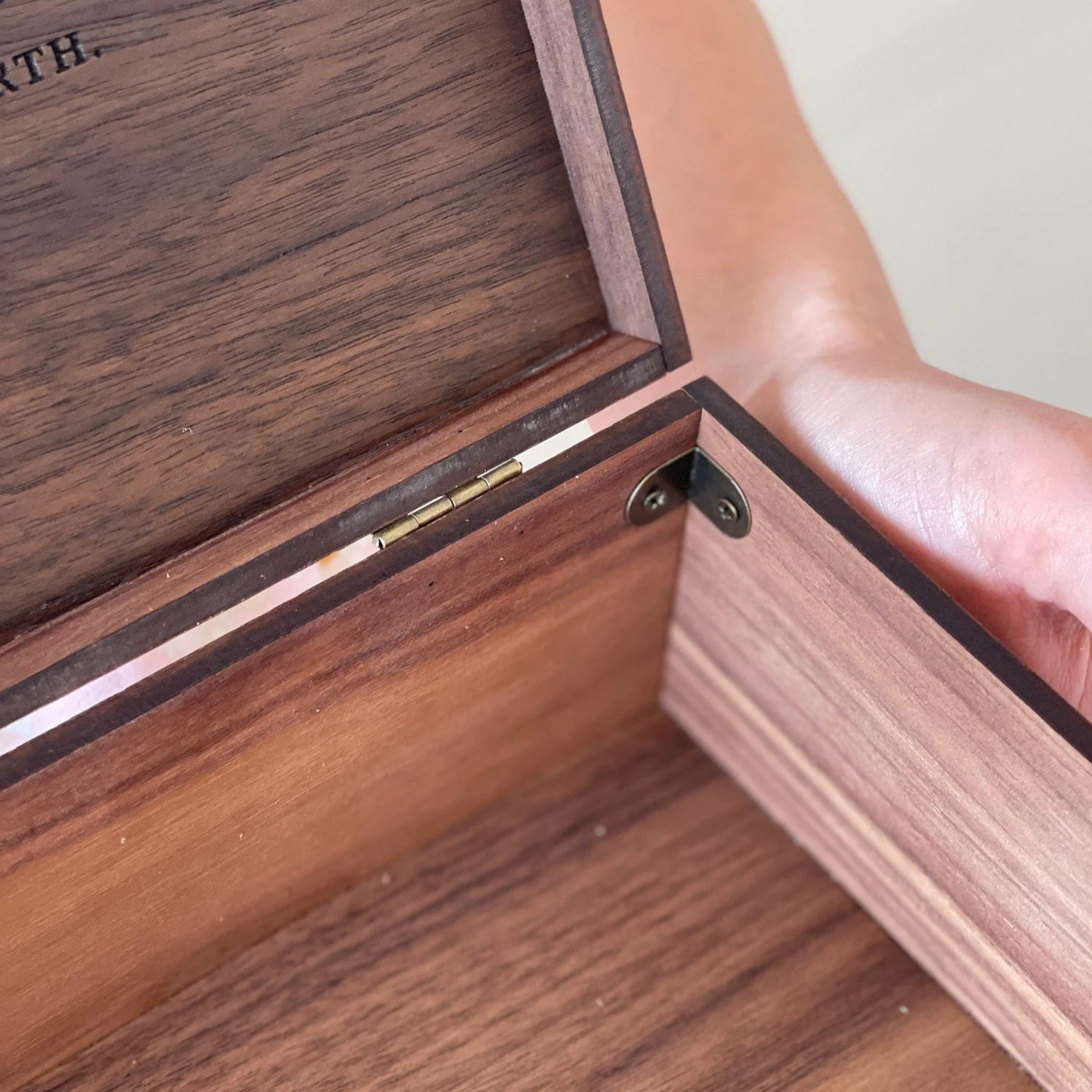 Wooden box with a hand opening it, engraved text visible