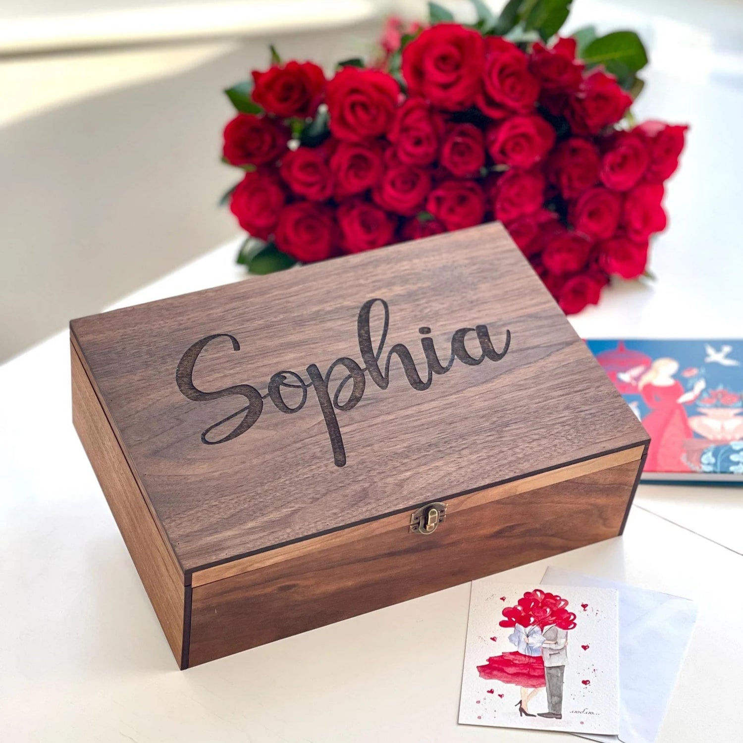 Wooden box with 'Sophia' engraved, red roses in the background