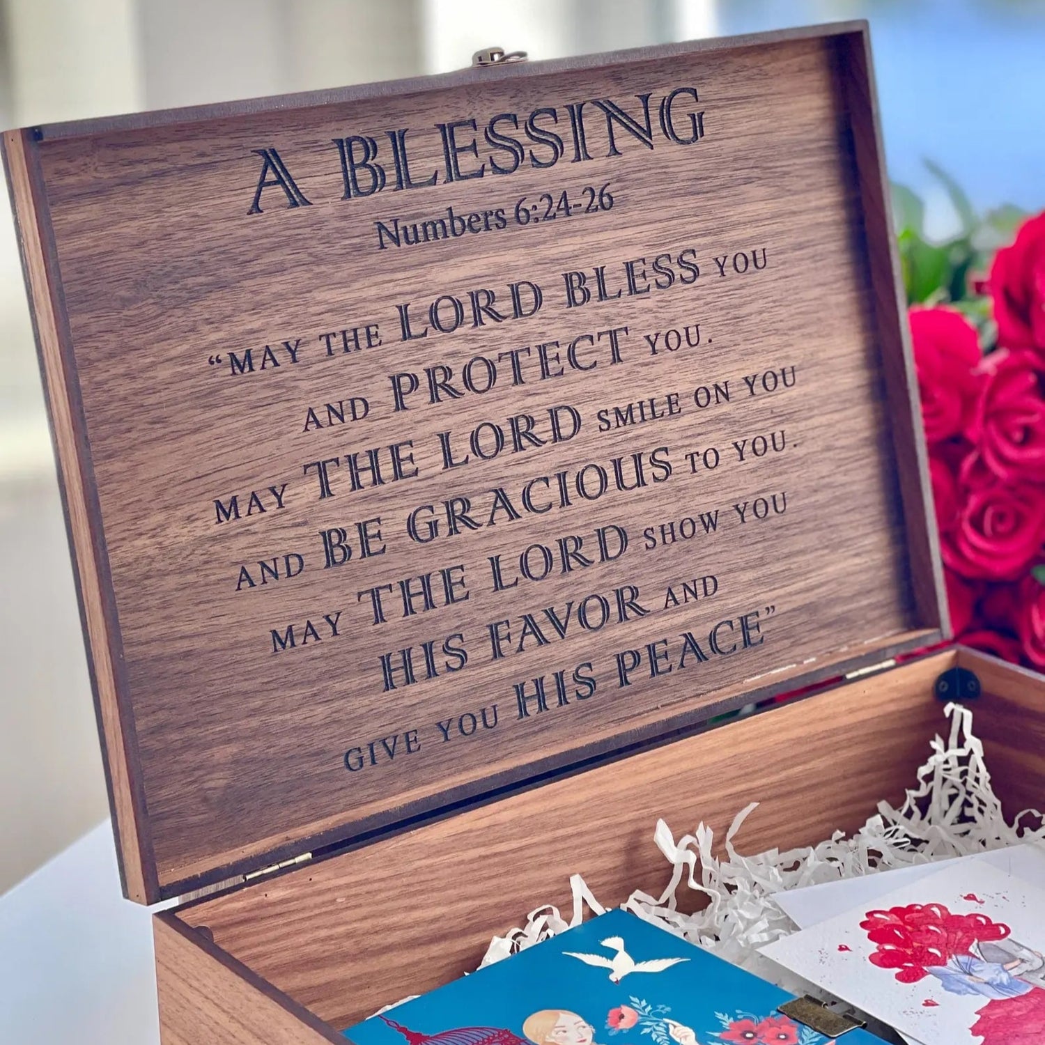 Wooden box with engraved text and flowers in the background