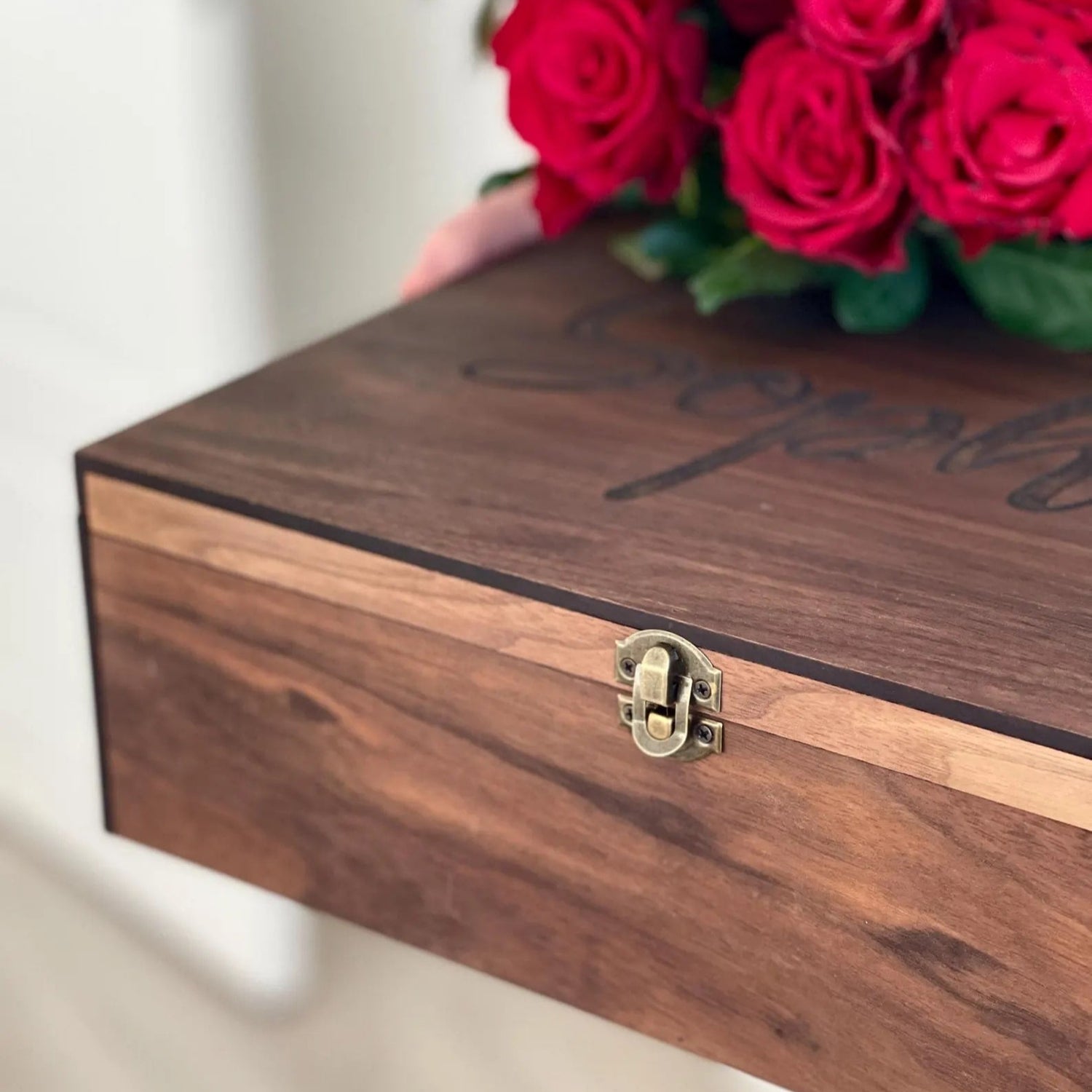 Wooden box with a gold clasp and a bouquet of red roses on a blurred background