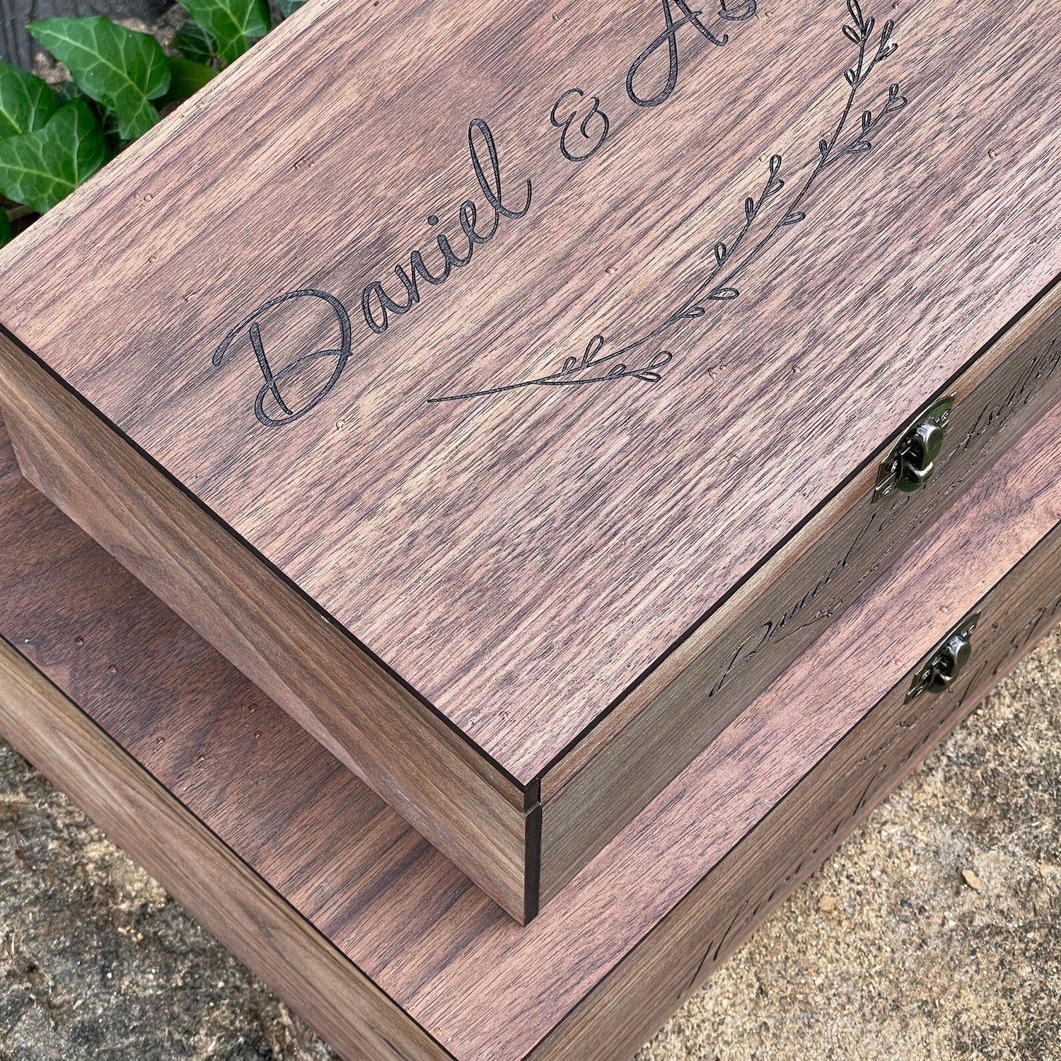 Wooden box with engraved names 'Daniel & A' on a stone surface