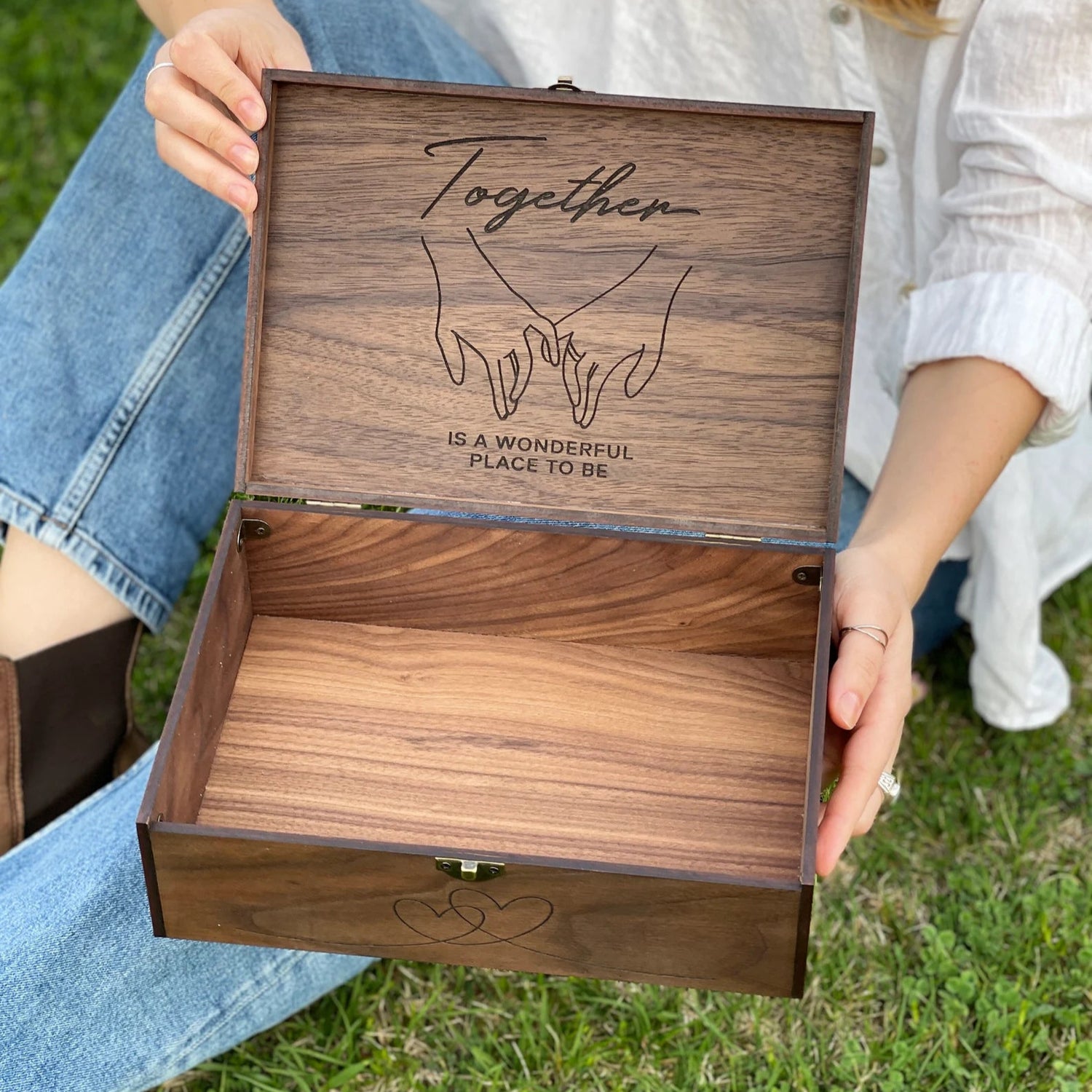 Wooden box with engraved text held by a person outdoors