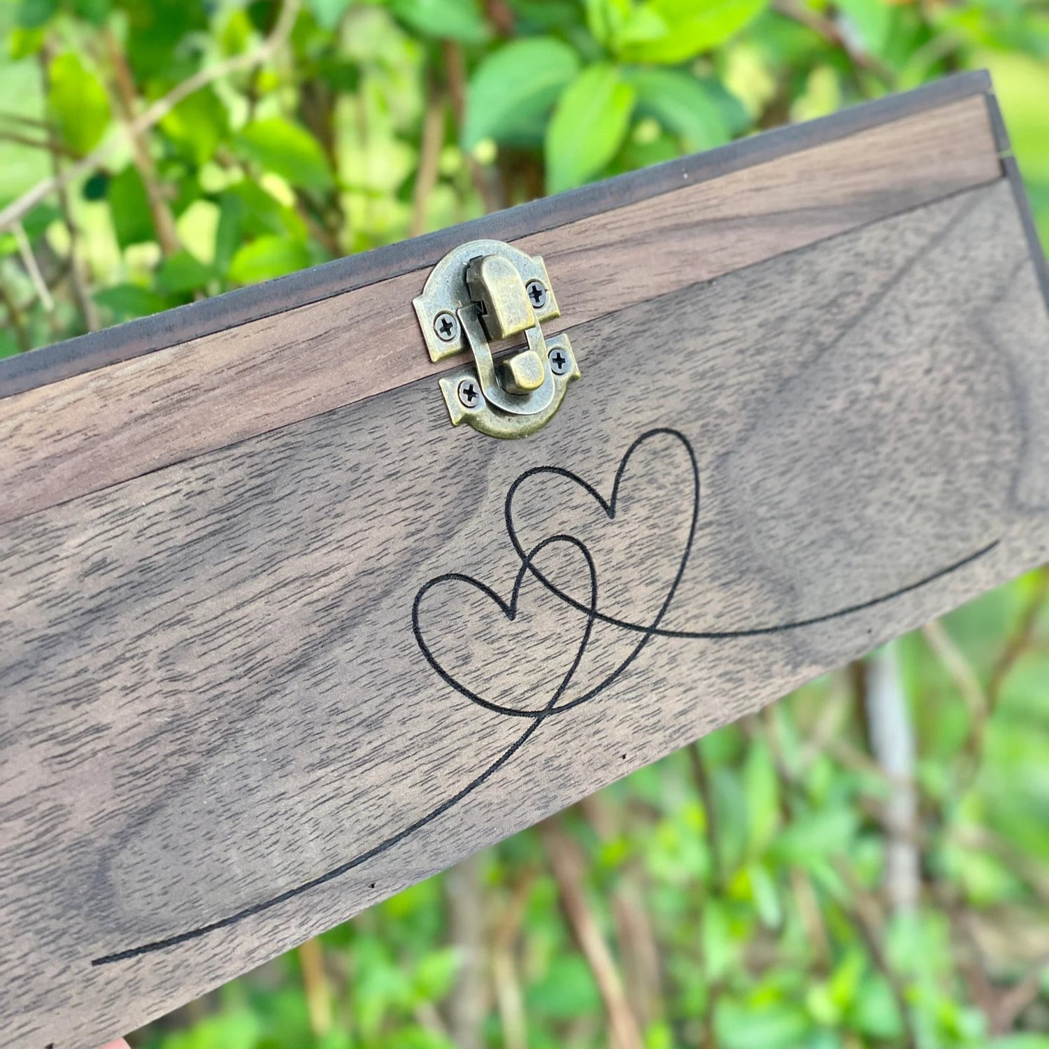 Wooden box with a decorative heart design on a green leafy background