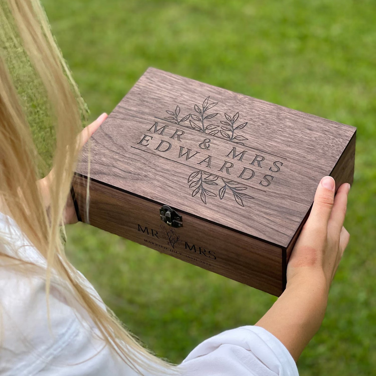 Wooden box engraved with 'MR & MRS EDWARDS' held by a person outdoors.
