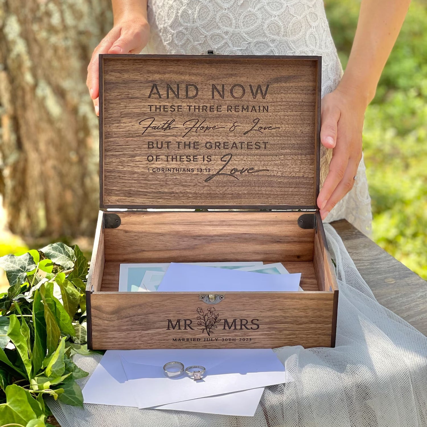 Wooden box with engraved text held by a person outdoors