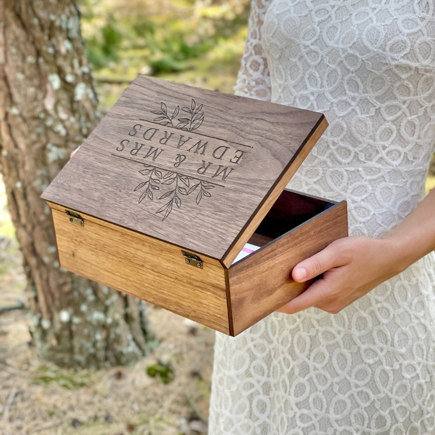 Wooden box with engraved text held by a person in a natural setting