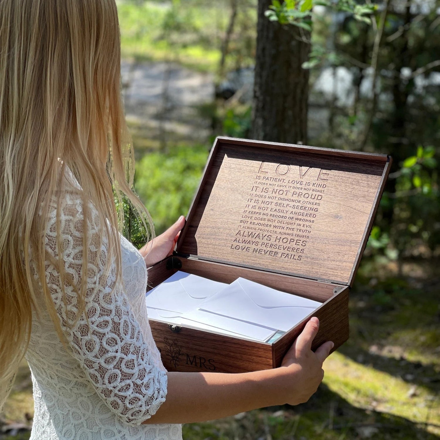 Woman holding a wooden box with engraved text in a natural setting