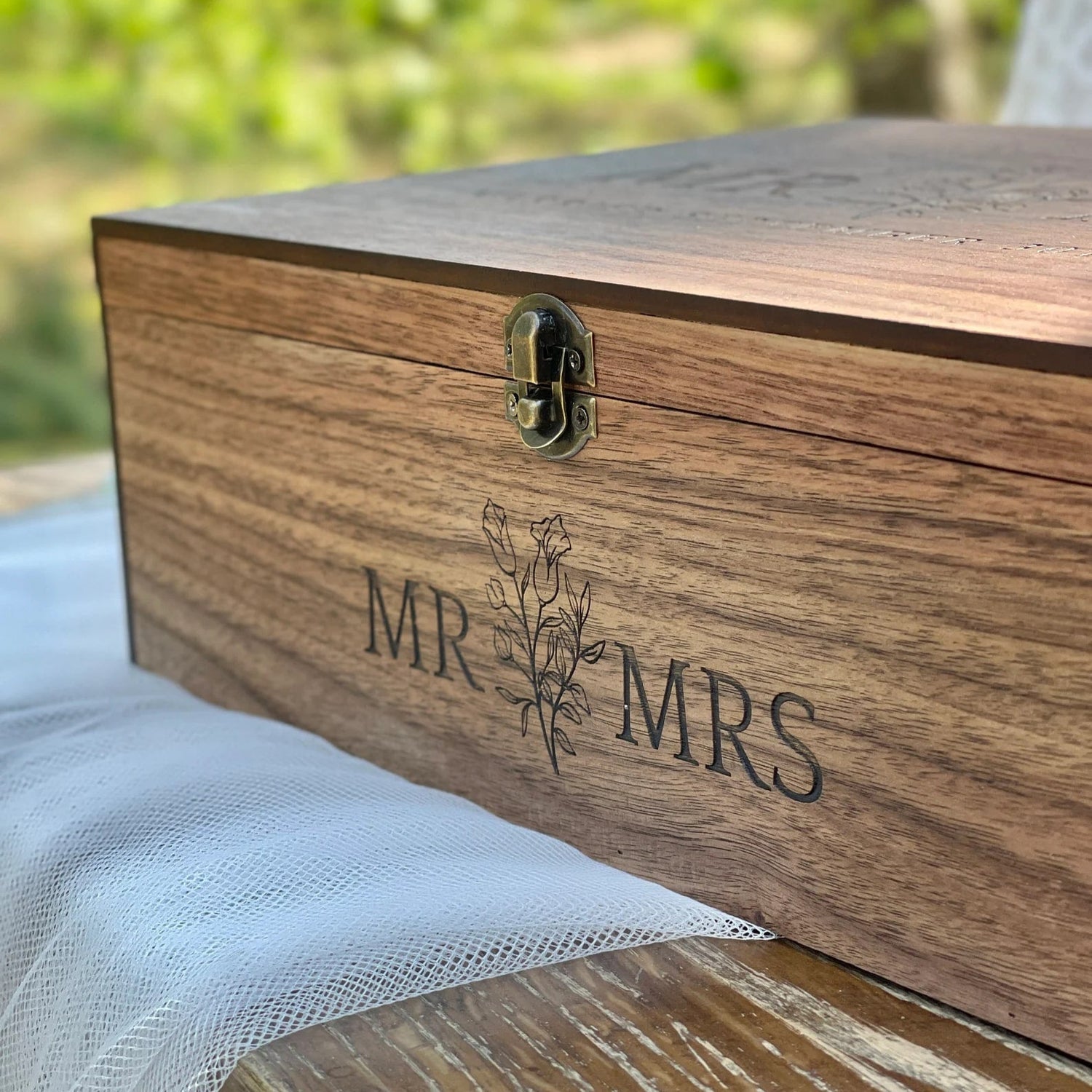 Wooden box with 'MR & MRS' engraving on a blurred natural background