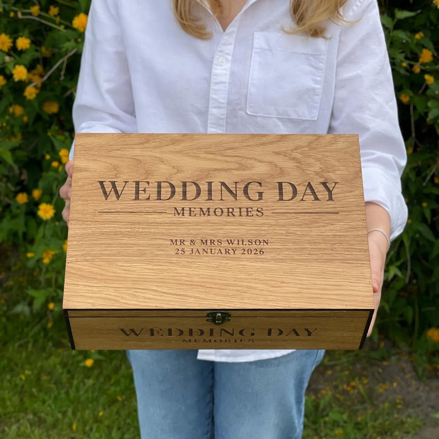 Person holding a wooden box engraved with 'Wedding Day Memories' in an outdoor setting.
