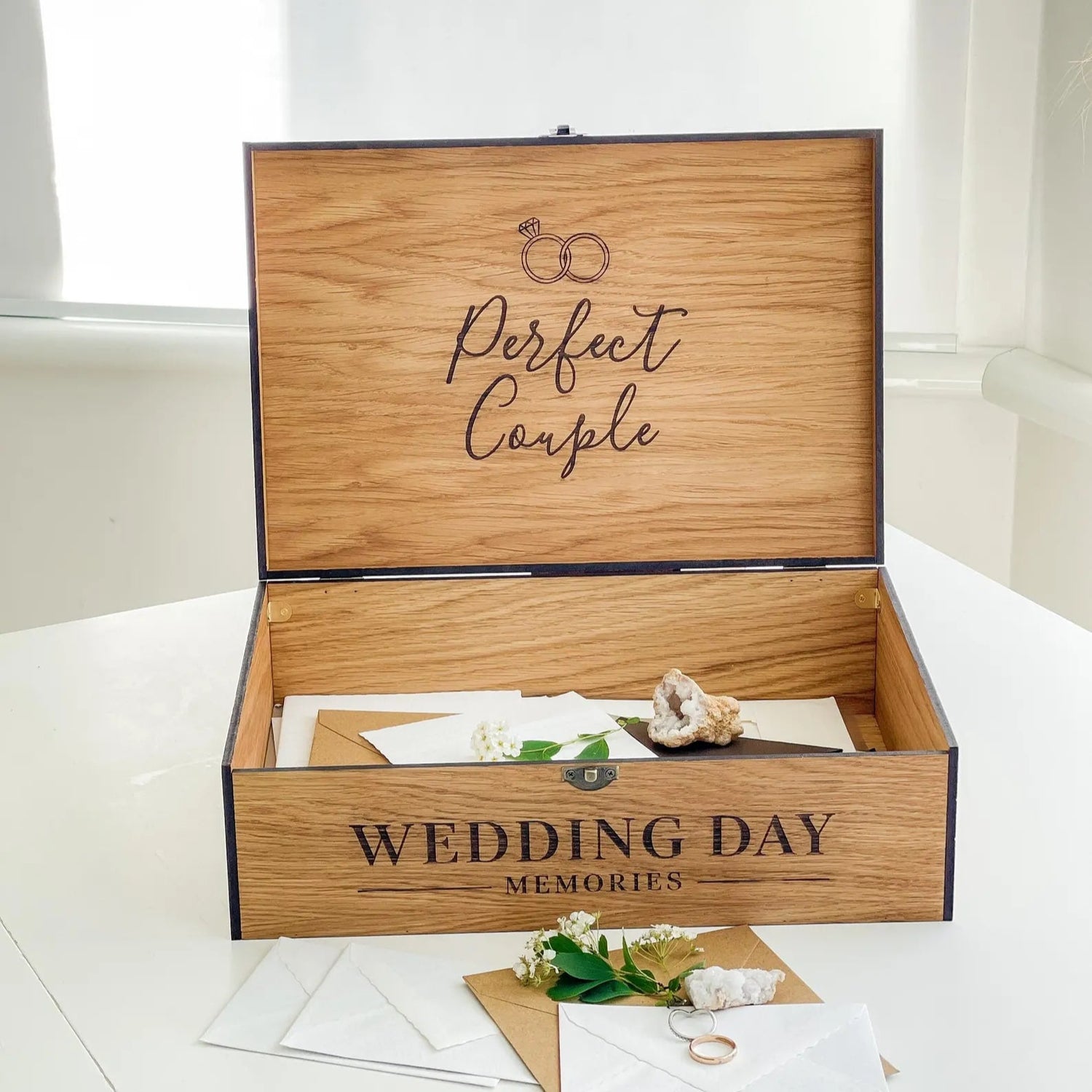 Wooden box labeled 'Perfect Couple Wedding Day Memories' on a white surface.