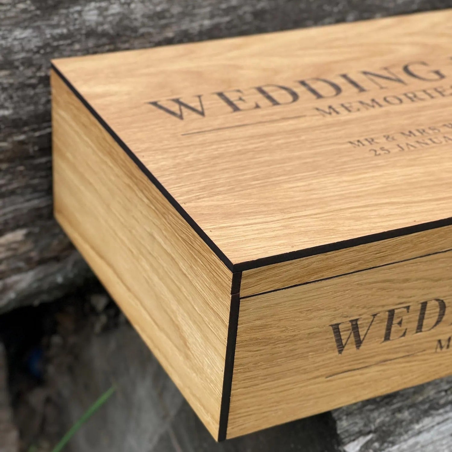Wooden box with engraved text on a stone surface