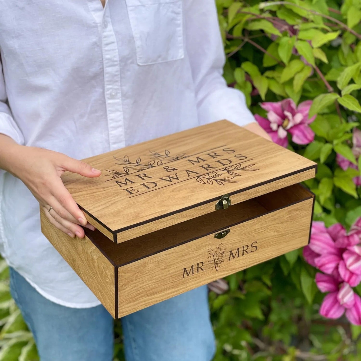 Person holding a wooden box engraved with 'Mr & Mrs' in a garden setting