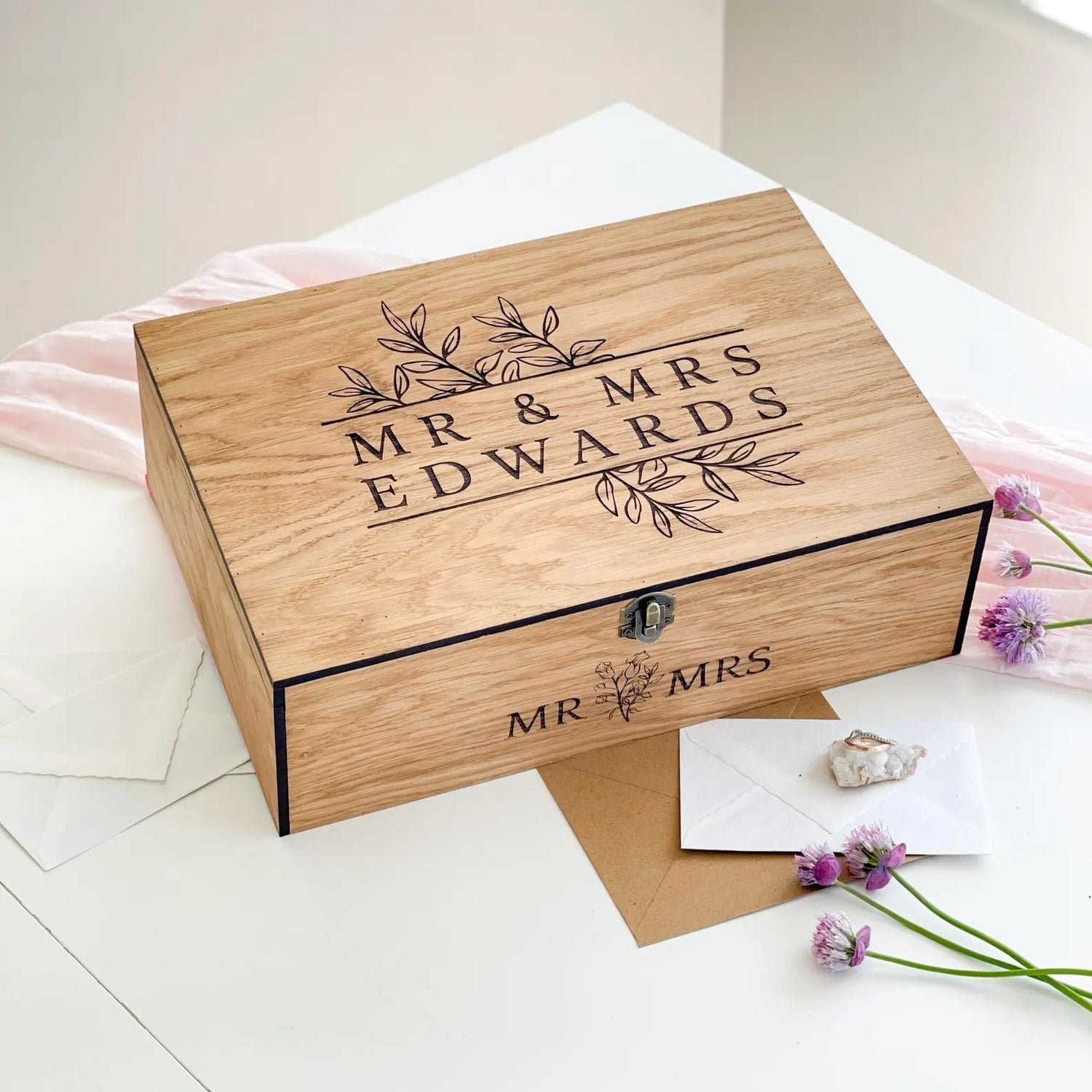Wooden box engraved with 'Mr & Mrs Edwards' on a light surface with flowers.