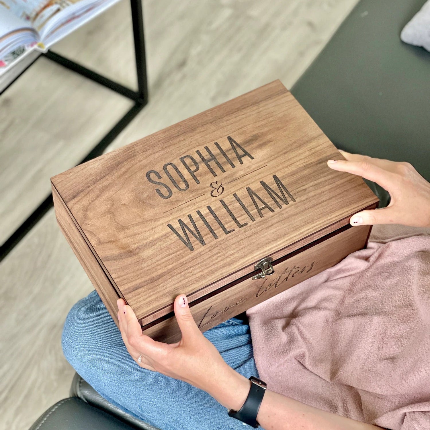 Wooden box with 'SOPHIA & WILLIAM' engraving held by a person on a light wooden floor.