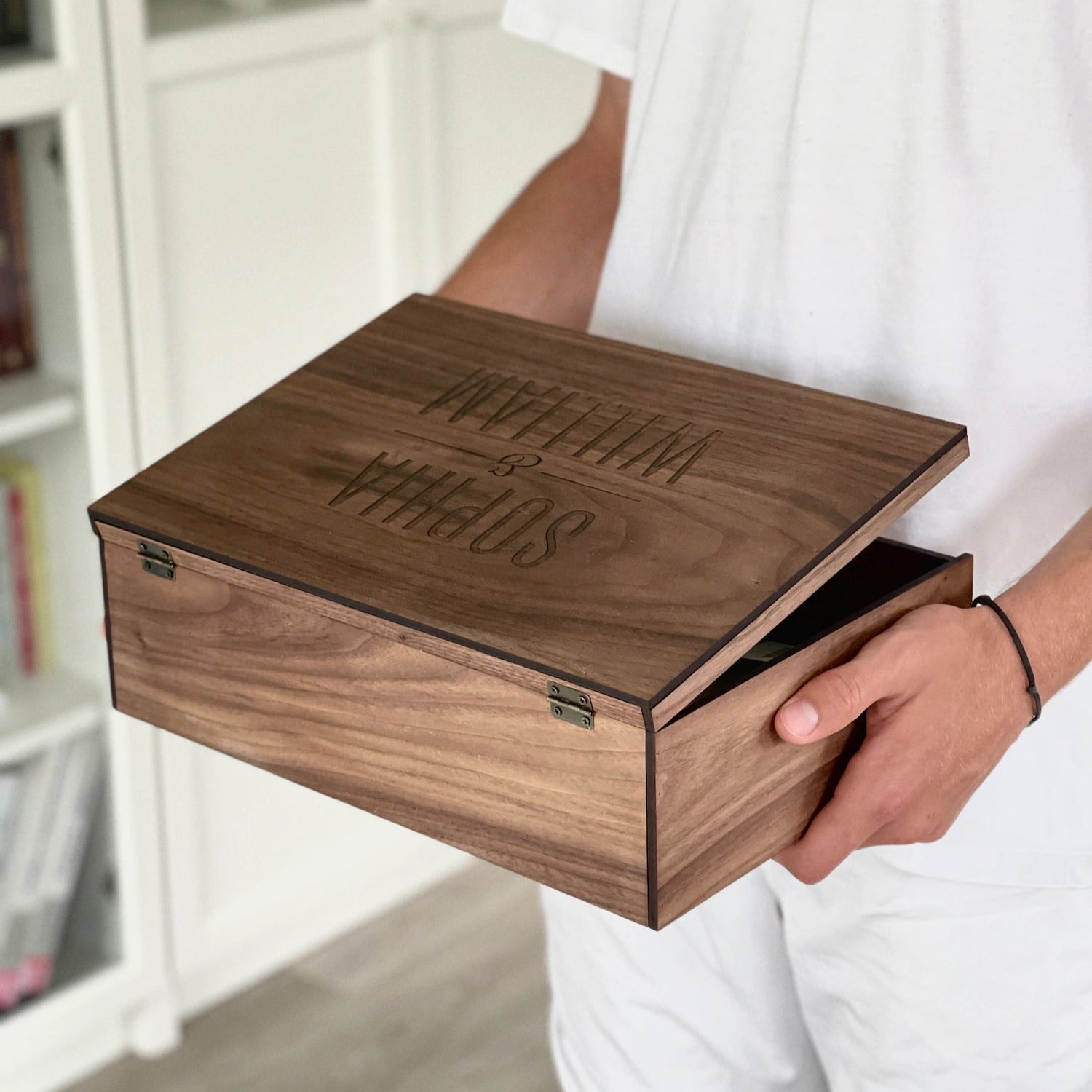 Person holding a wooden box with 'William & Son' engraving, wearing a Levi's shirt.