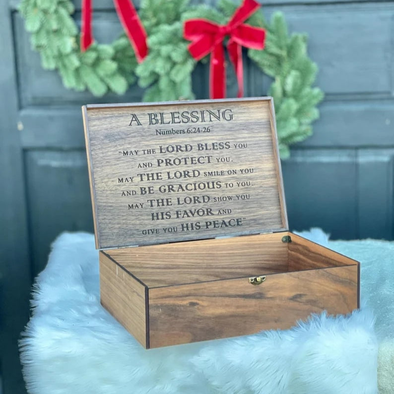 Wooden box with engraved text in front of a door with wreaths.