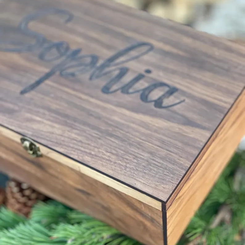 Wooden box with 'Sophia' engraved on it, surrounded by greenery