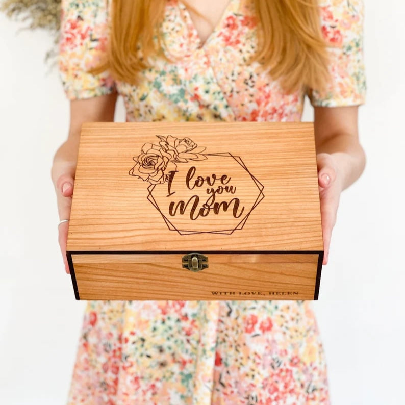 Person holding a wooden box with 'I love you Mom' engraving