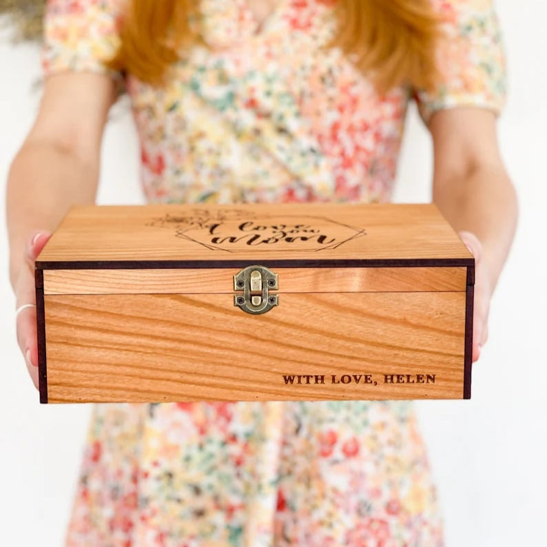 Person holding a wooden box engraved with 'I love you always' and 'With Love, Helen'.