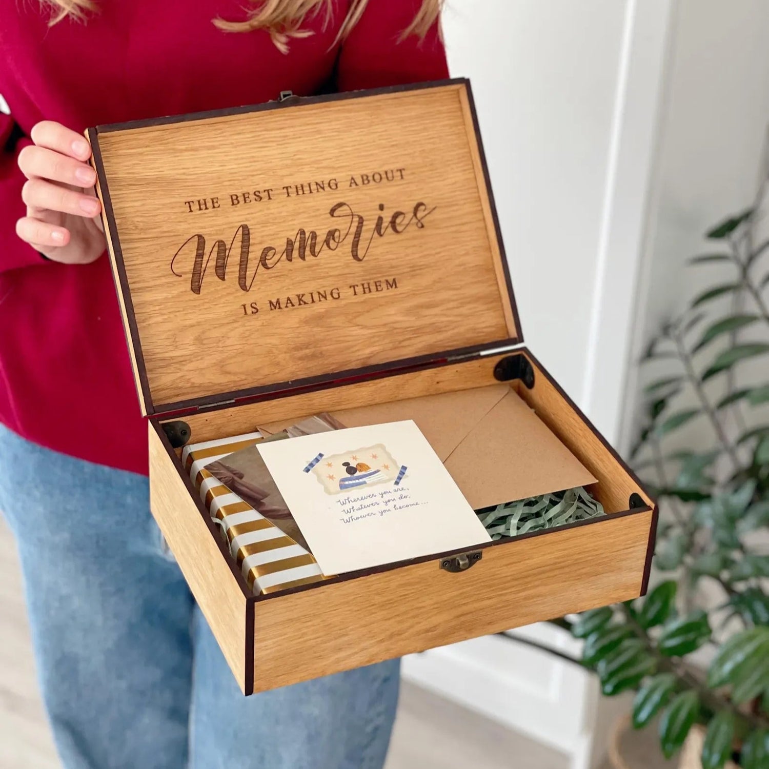 Person holding a wooden box with engraved text and items inside.