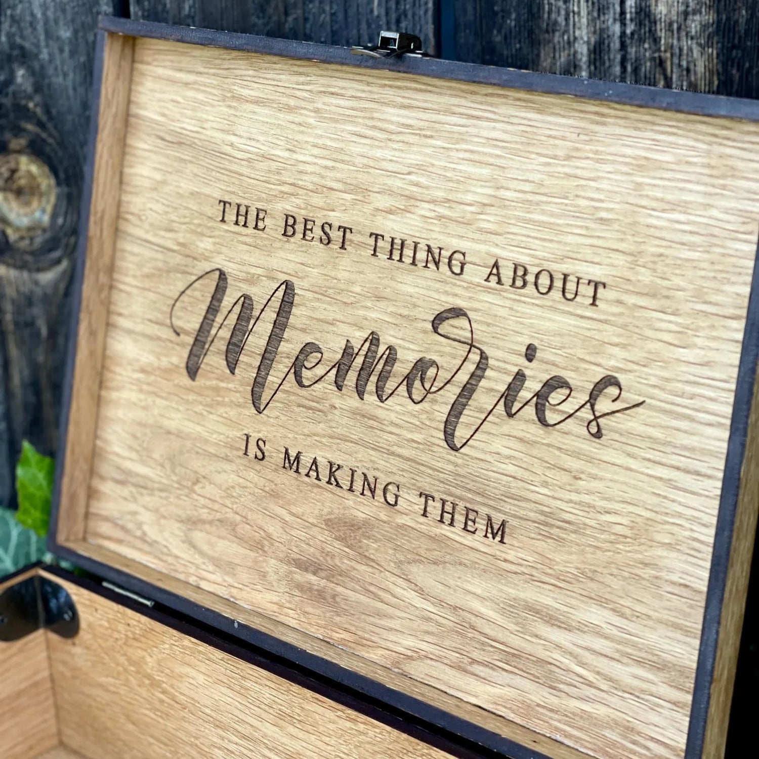Wooden box with engraved text 'The best thing about memories is making them' against a wooden background.