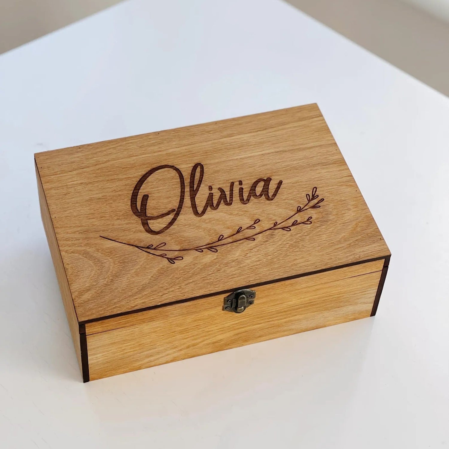 Wooden box with 'Olivia' engraved on it, placed on a white surface.