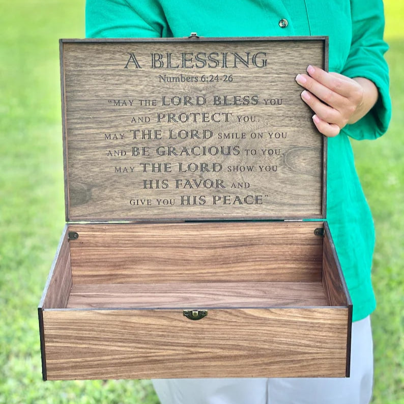 Person holding a wooden box with engraved text outdoors